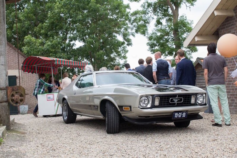 Klassieke Mustang trouwauto bij feestlocatie met gasten