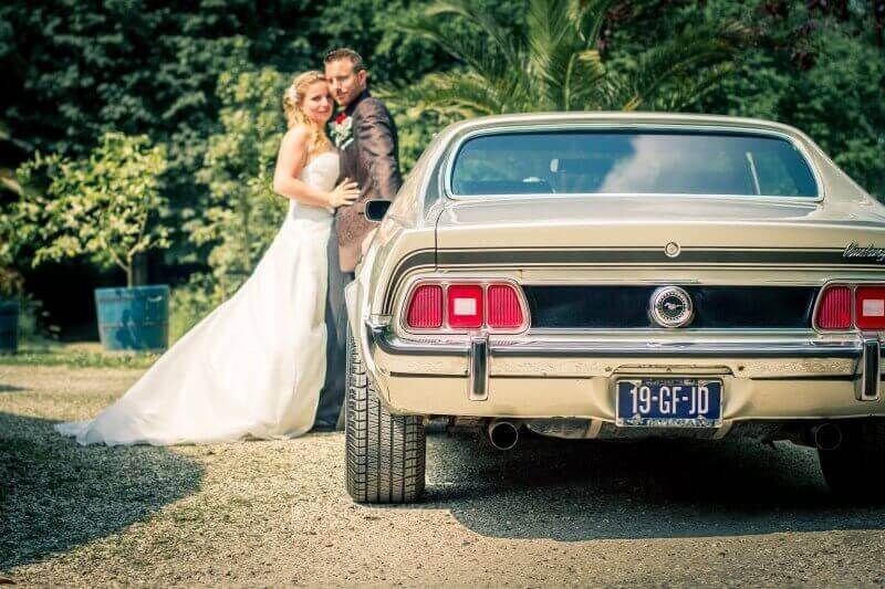 Bruidspaar poseert bij klassieke Mustang trouwauto